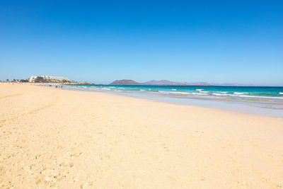 Scenic view of beach against clear blue sky