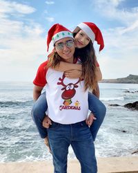 Portrait of boyfriend piggybacking girlfriend at beach against sky