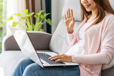Midsection of woman using mobile phone at home