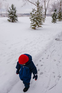 Boy walking on snow covered field