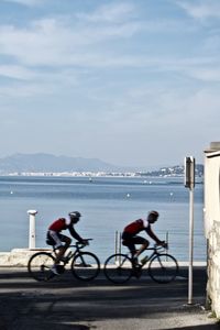 People riding bicycles on road against sky