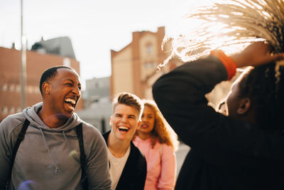 Happy male and female friends having fun in city during sunny day