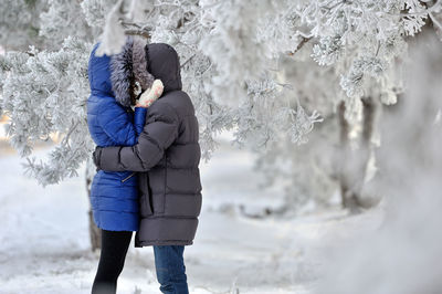 Side view of couple hugging in the snow