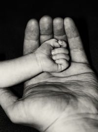 Close-up of baby hand against black background