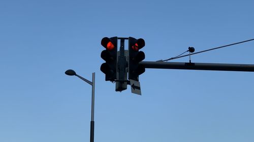 Low angle view of road signal against clear blue sky