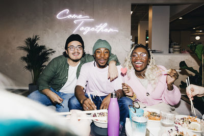 Portrait of cheerful multiracial male and female friends enjoying meal in college dorm