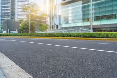 Empty road by building in city against sky