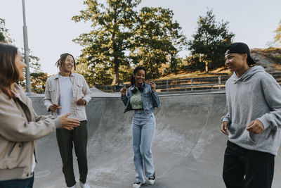 Teenagers standing in skate park, talking and laughing