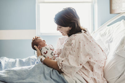 Side view of mother looking lovingly at newborn son in hospital