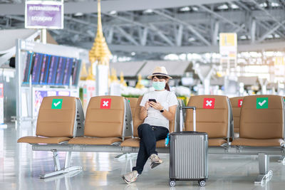 Full length of woman sitting on seat in airport