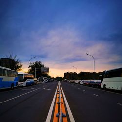 Vehicles on road against sky at sunset