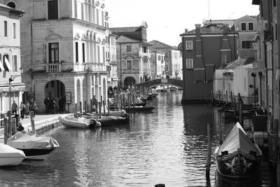 Sailboats moored on canal amidst buildings in city