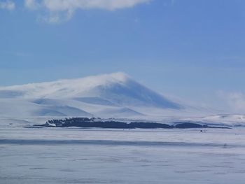 Scenic view of sea by snowcapped mountains against sky