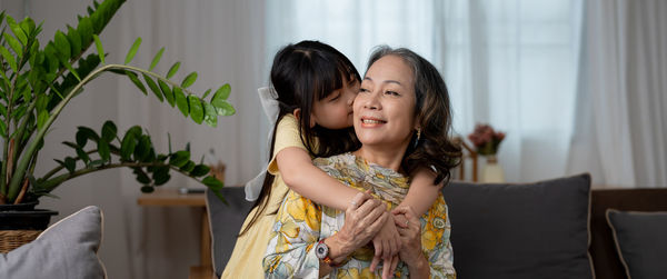 Granddaughter embracing grandmother at home