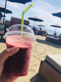 Close-up of hand holding drink at beach