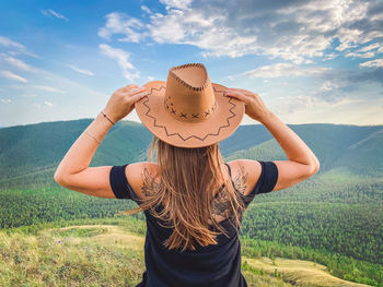 Rear view of woman standing on field against sky