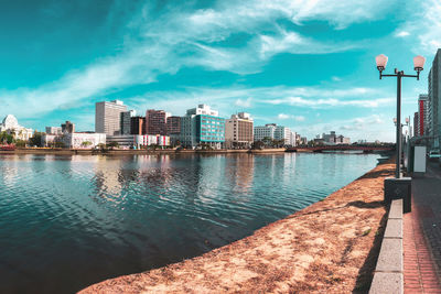 River by buildings in city against sky