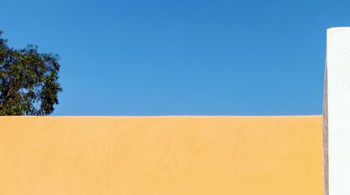 Low angle view of yellow built structure against blue sky