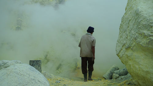 Rear view of man standing on rock