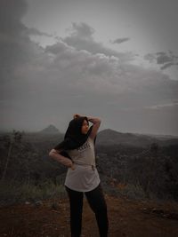 Teenage girl standing on mountain against sky