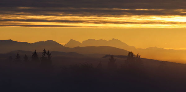 Scenic view of silhouette mountains against orange sky