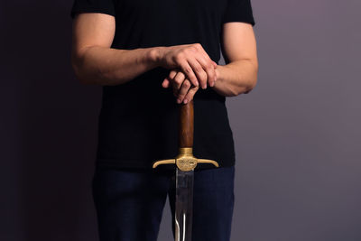 Midsection of man holding cigarette against black background