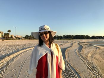 Portrait of smiling woman standing at beach against clear sky