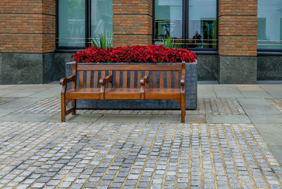 View of red bench on footpath against building