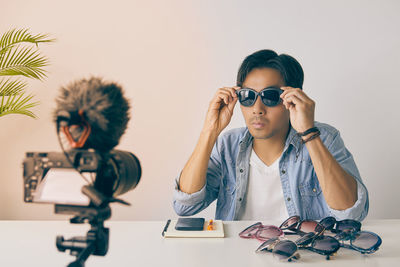Portrait of boy holding camera on table
