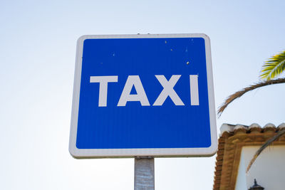 Low angle view of road sign against clear blue sky