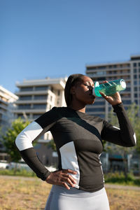 Ethnic athlete drinking water during break