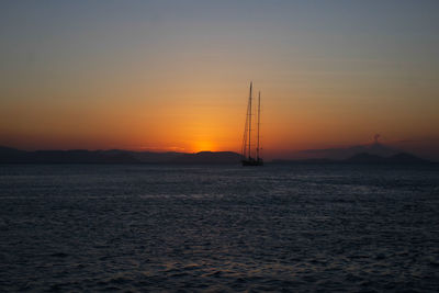 Silhouette sailboat on sea against romantic sky at sunset