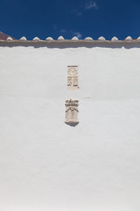 Low angle view of symbol carving on white church wall