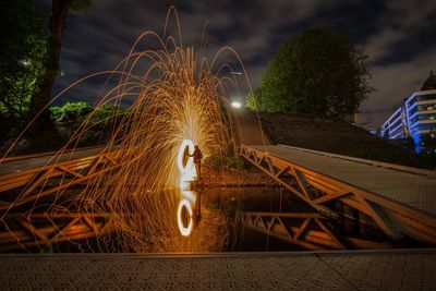 Man standing in illuminated park against sky at night