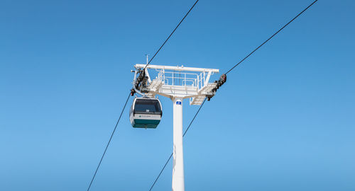 Low angle view of overhead cable car against clear blue sky