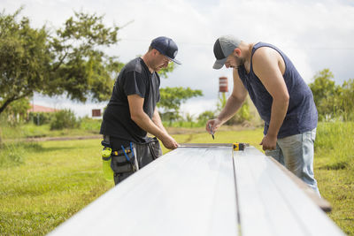 Two men preparing steel excursion for solar panel installation.