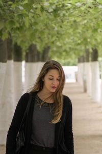 Young woman standing against tree