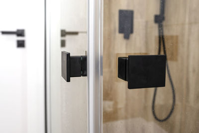 Enclosed glass shower door with matte black handles in a modern bathroom.