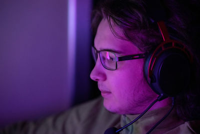 Young man with glasses and headphones plays computer games