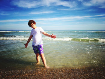 Boy standing on beach against sky