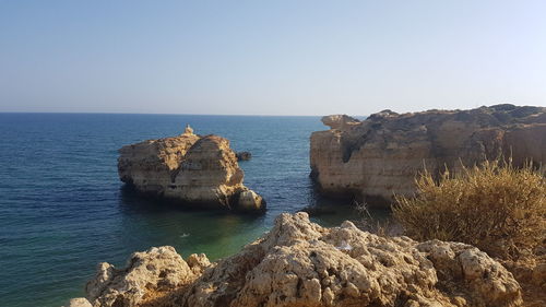 Scenic view of rocks in sea against clear sky