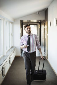 Businessman with suitcase walking in hotel corridor