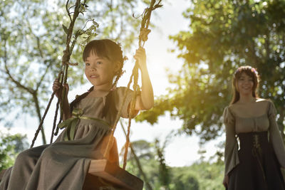 Mother looking at daughter sitting on swing