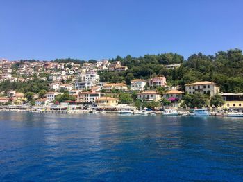 View of townscape by sea against clear blue sky