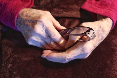 Close-up of man holding eyeglasses on table