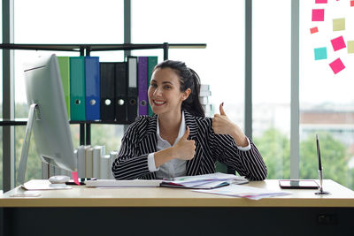 Portrait of a smiling young woman sitting on table