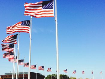 Low angle view of american flags against clear blue sky