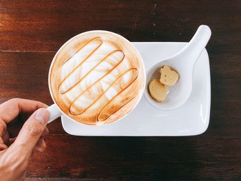 Cropped hand holding coffee cup on wooden table