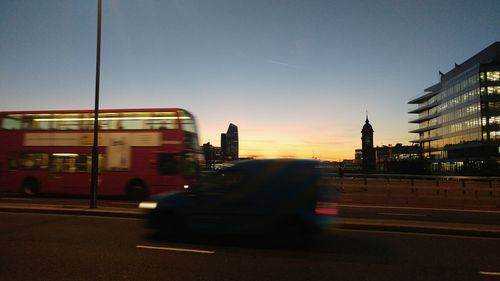 Cars on road in city against sky during sunset