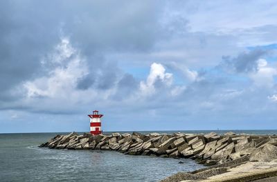 Lighthouse by sea against sky